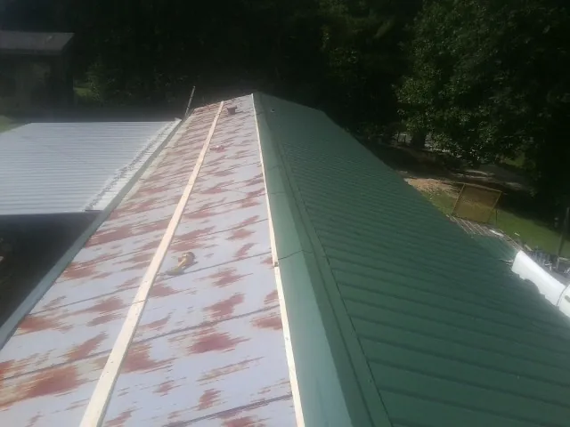 Old rusted panels beside newly installed green metal roofing — Wind Damage Roof Repair by Roofing Brothers in North Fork