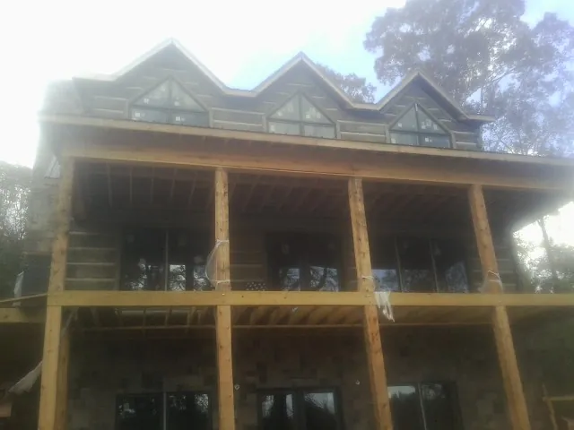 Dormers and porch framing on a large log home under construction — Roof Coating work by our crew in North Fork