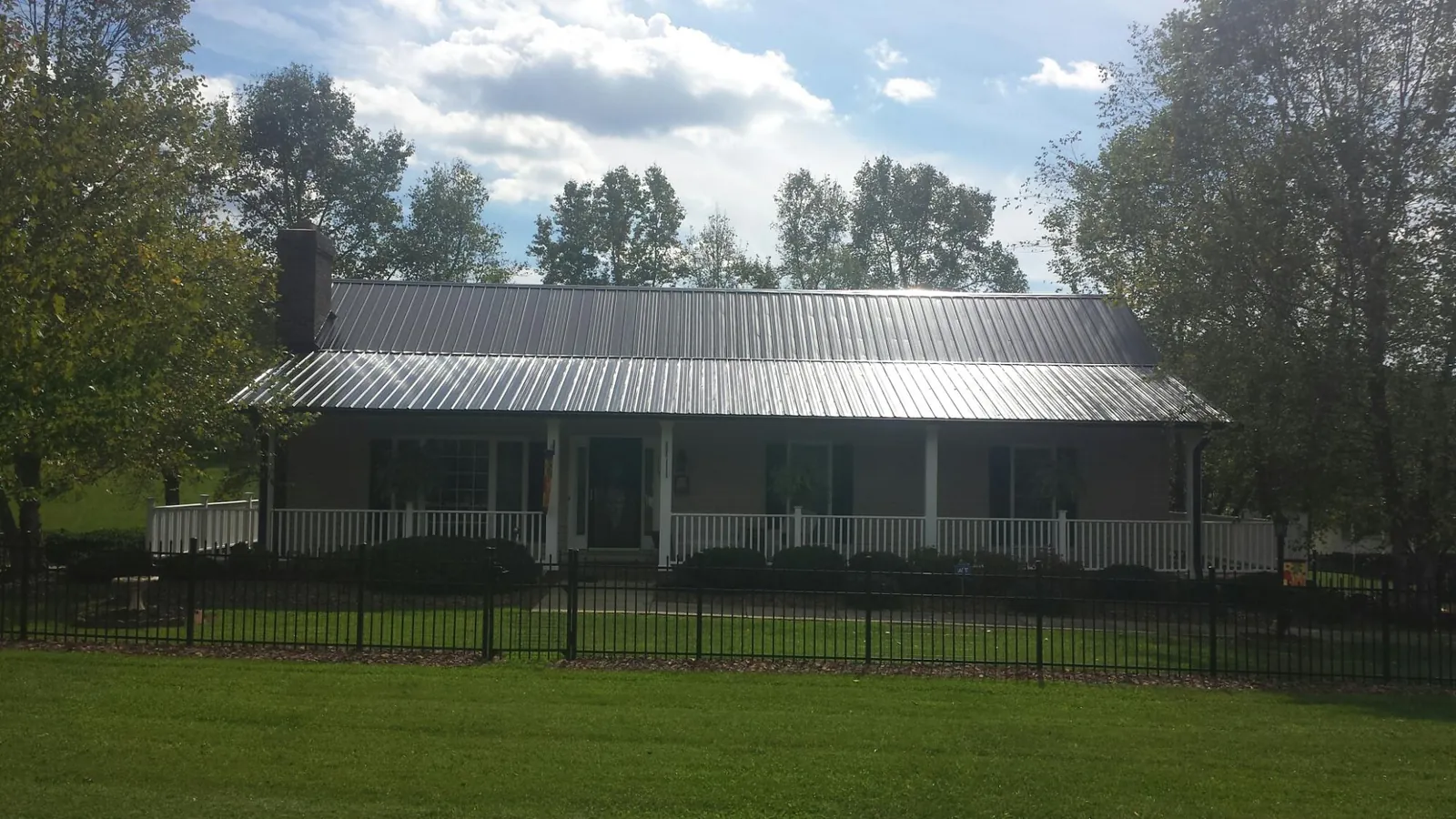 Gray metal roof on a brick ranch with a full width front porch — Gutter Guard Installation work by our crew in North Fork