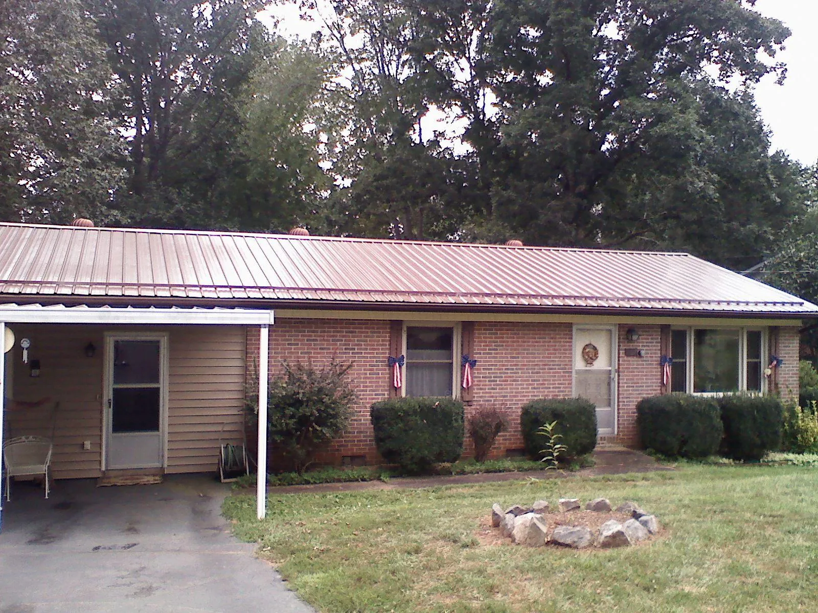Bronze metal roof and carport on a brick ranch home — Roof Repair work by our crew in North Fork