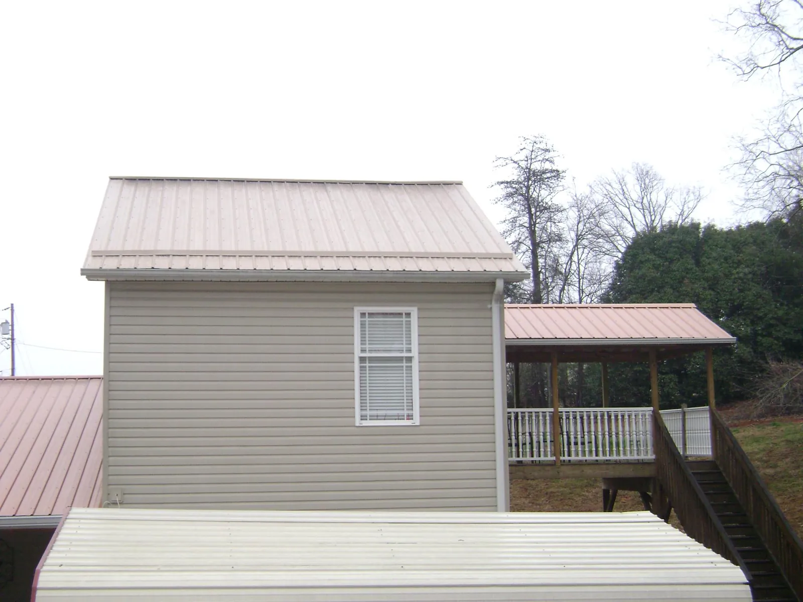 Tan metal roofs on a two story addition and attached porch, from a Roof Replacement job in North Fork