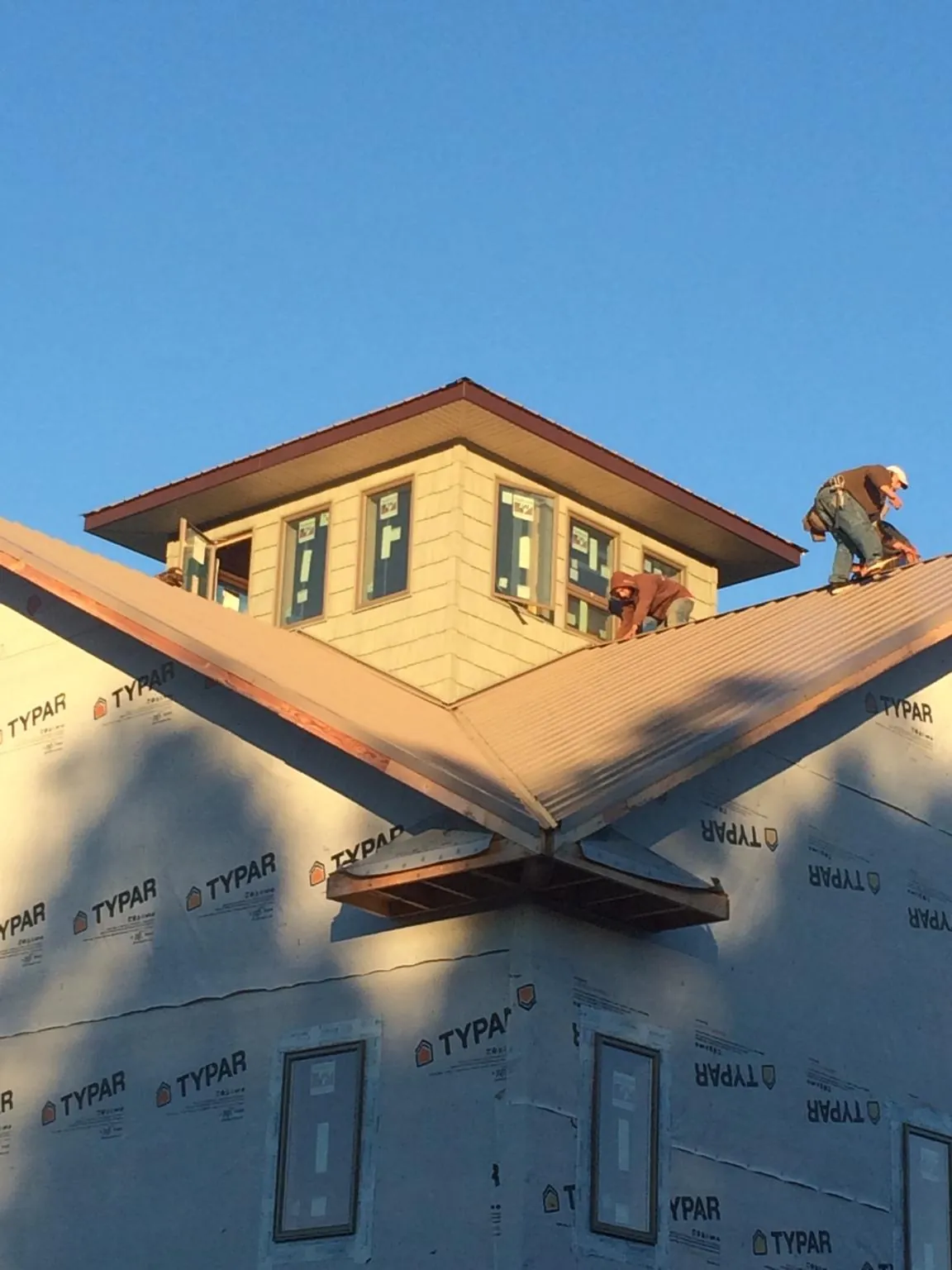 Roofers working around a rooftop cupola on a new metal roof at sunset — Roof Waterproofing in North Fork by Roofing Brothers